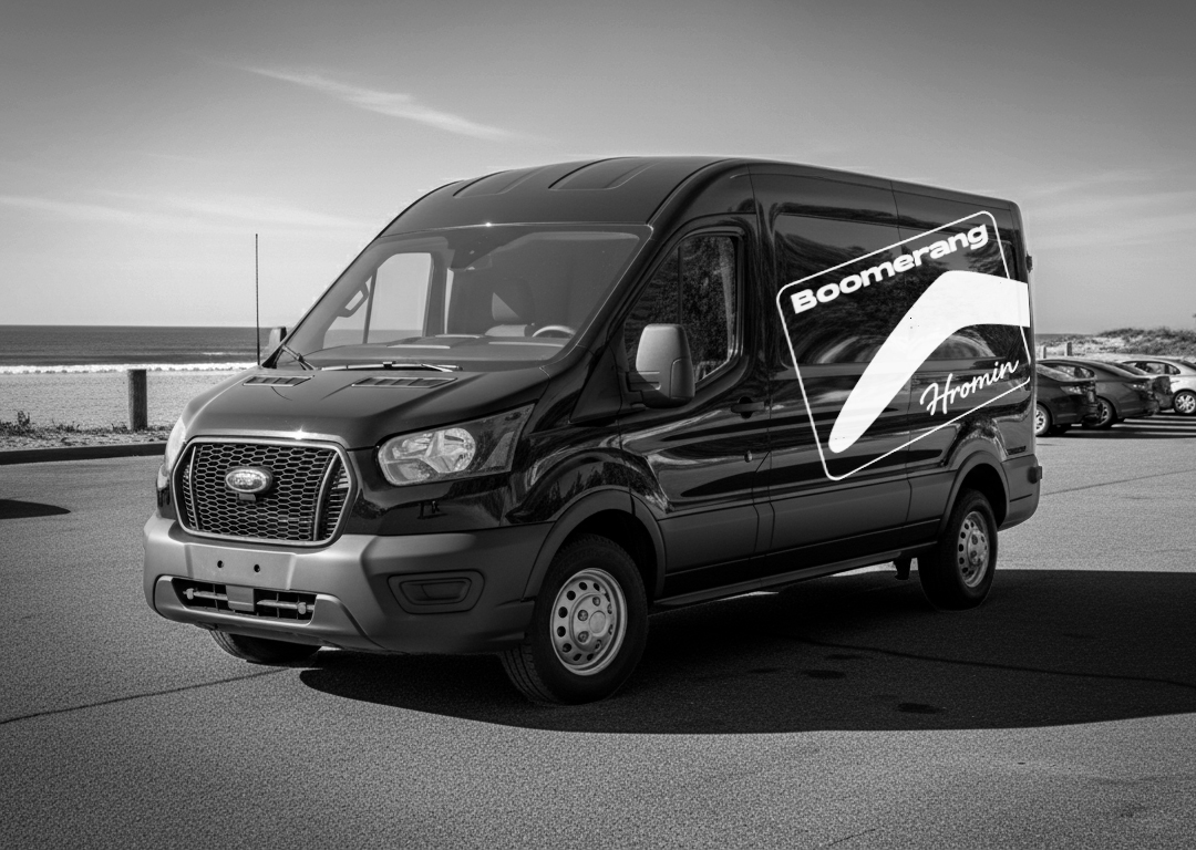 Boomerang Homin branded Ford Transit van wrap — black and white with logo at beach parking lot